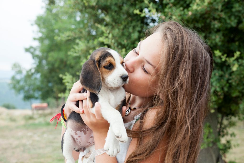 femme qui porte un chiot et lui fait un bisou