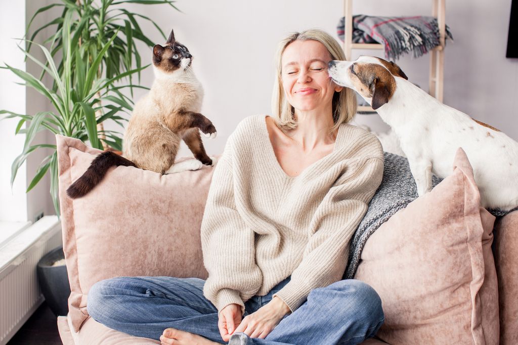 un chat et un chien à côté d'une femme assise en tailleur