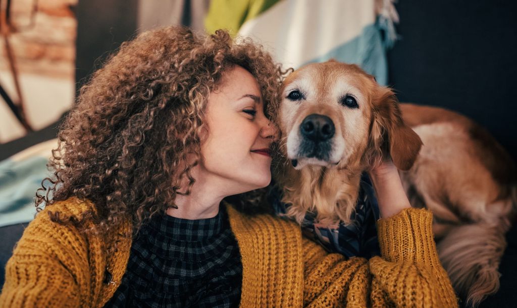 Une femme enlace un chien qui est allongé à côté d’elle et semble calme