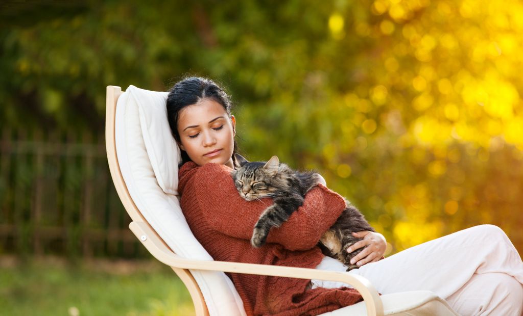 femme qui dort sur une chaise de jardin avec un chat endormi dans ses bras