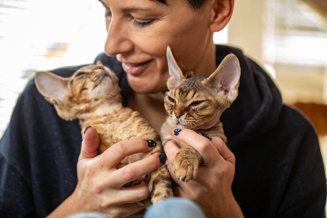 Une femme tient deux chats dans ses bras