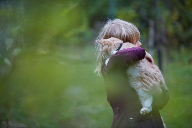 Petite fille qui fait un câlin à un chat roux