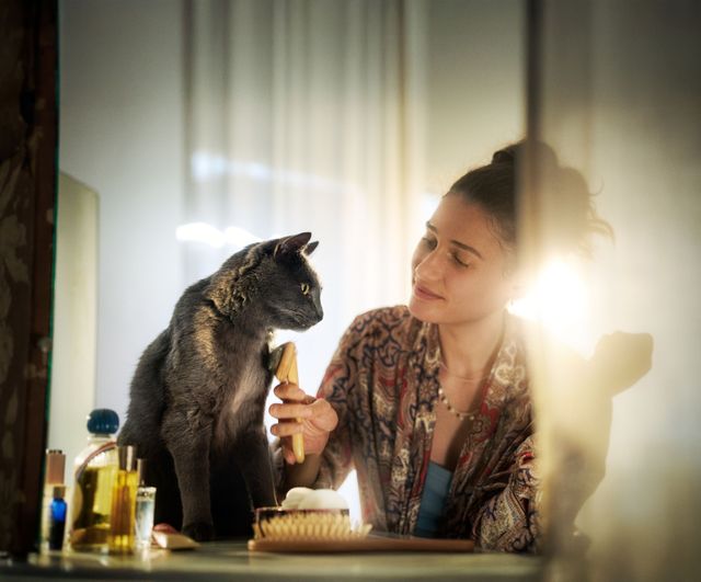 Une femme caresse un chat sur la table