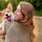 Femme qui tient un corgi qui sourit dans ses bas