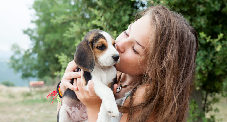 Petite fille donnant un baiser à un chiot dans ses bras